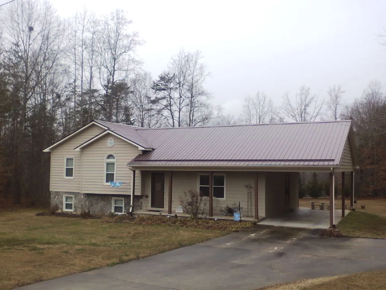 Burgundy metal roof on a tan split level home with an attached carport in Columbus